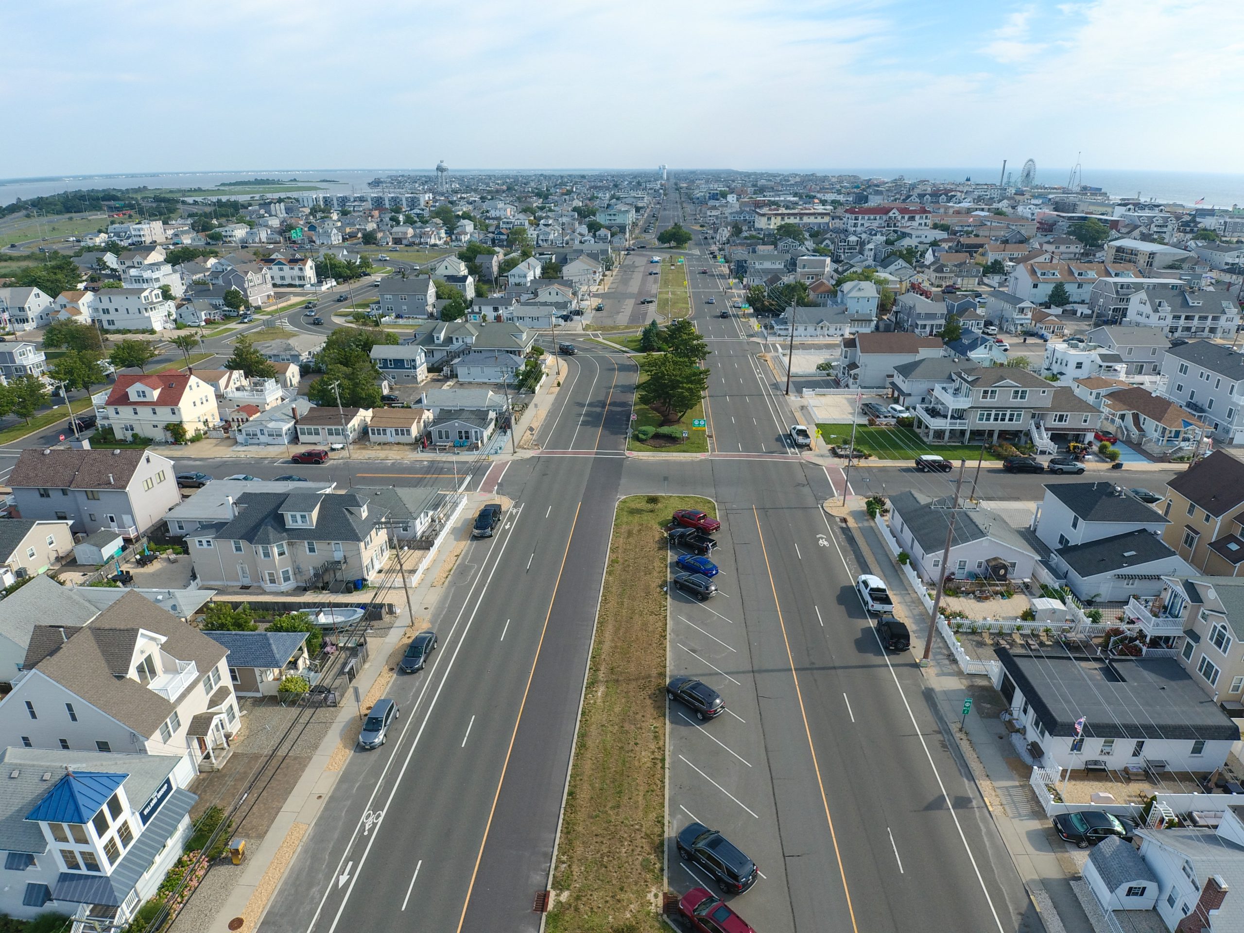 Aerial view north along Central Avenue in Seaside Park, with the barrier island rooftops on both sides and the boardwalk amusement pier on the horizon.